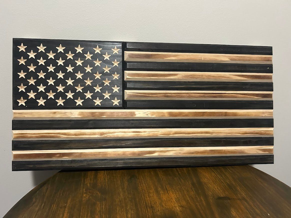 Wooden American flag, black and natural wood stripes, star field with cut-out stars.