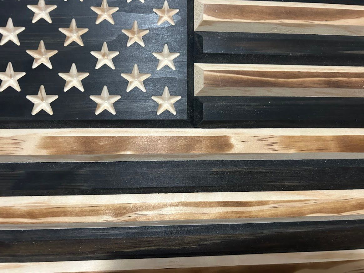 Wooden American flag, black and natural wood stripes, star field with cut-out stars.
