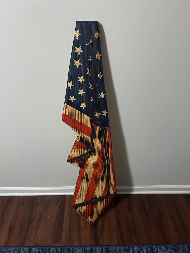 American flag wall hanging against a gray wall, brown floor.