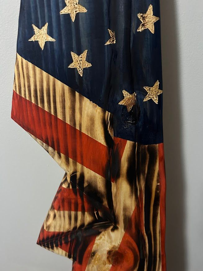 American flag wall hanging against a gray wall, brown floor.