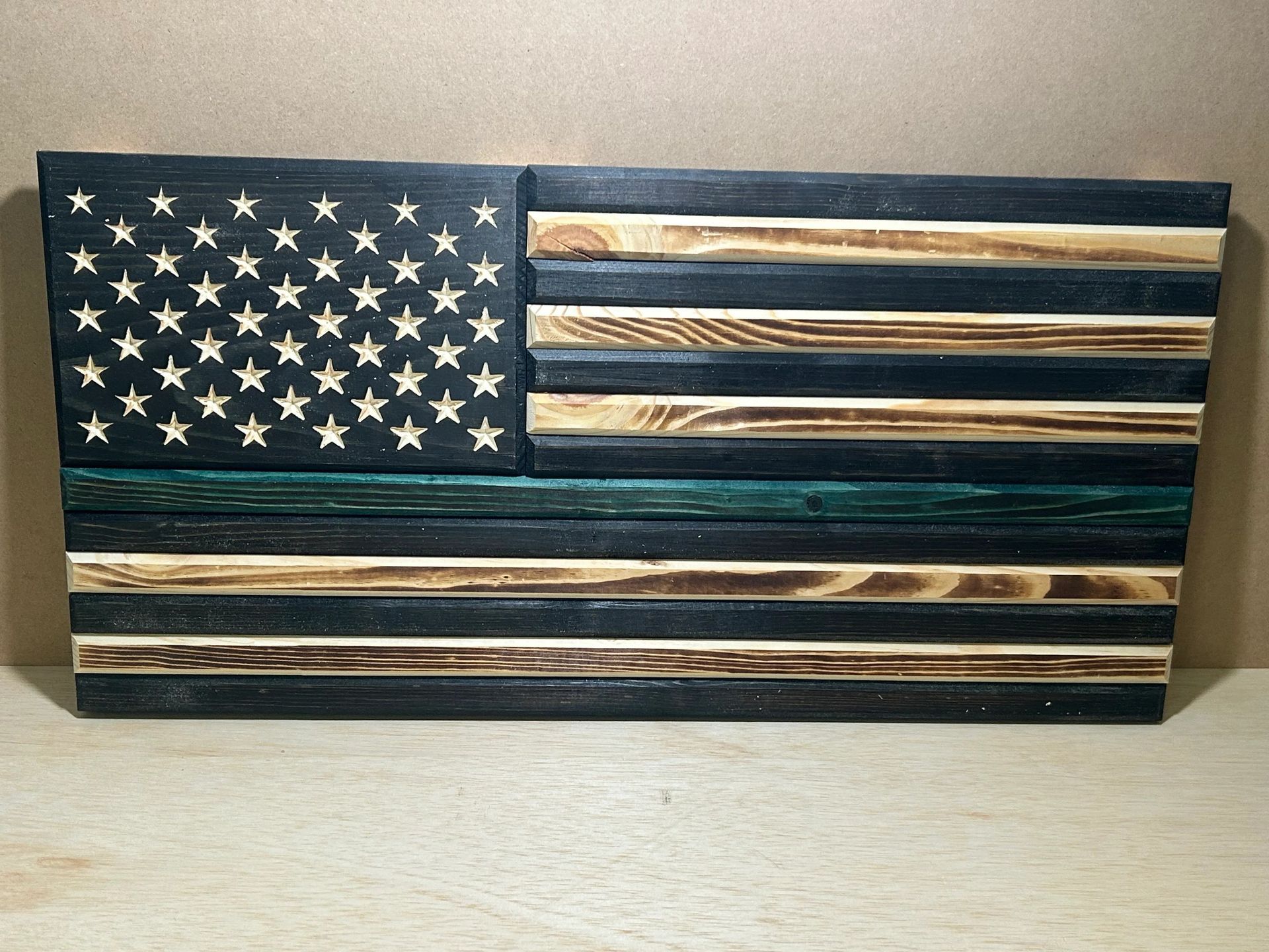 Wooden American flag with black, green, and natural wood stripes. Stars are carved out of the black field.