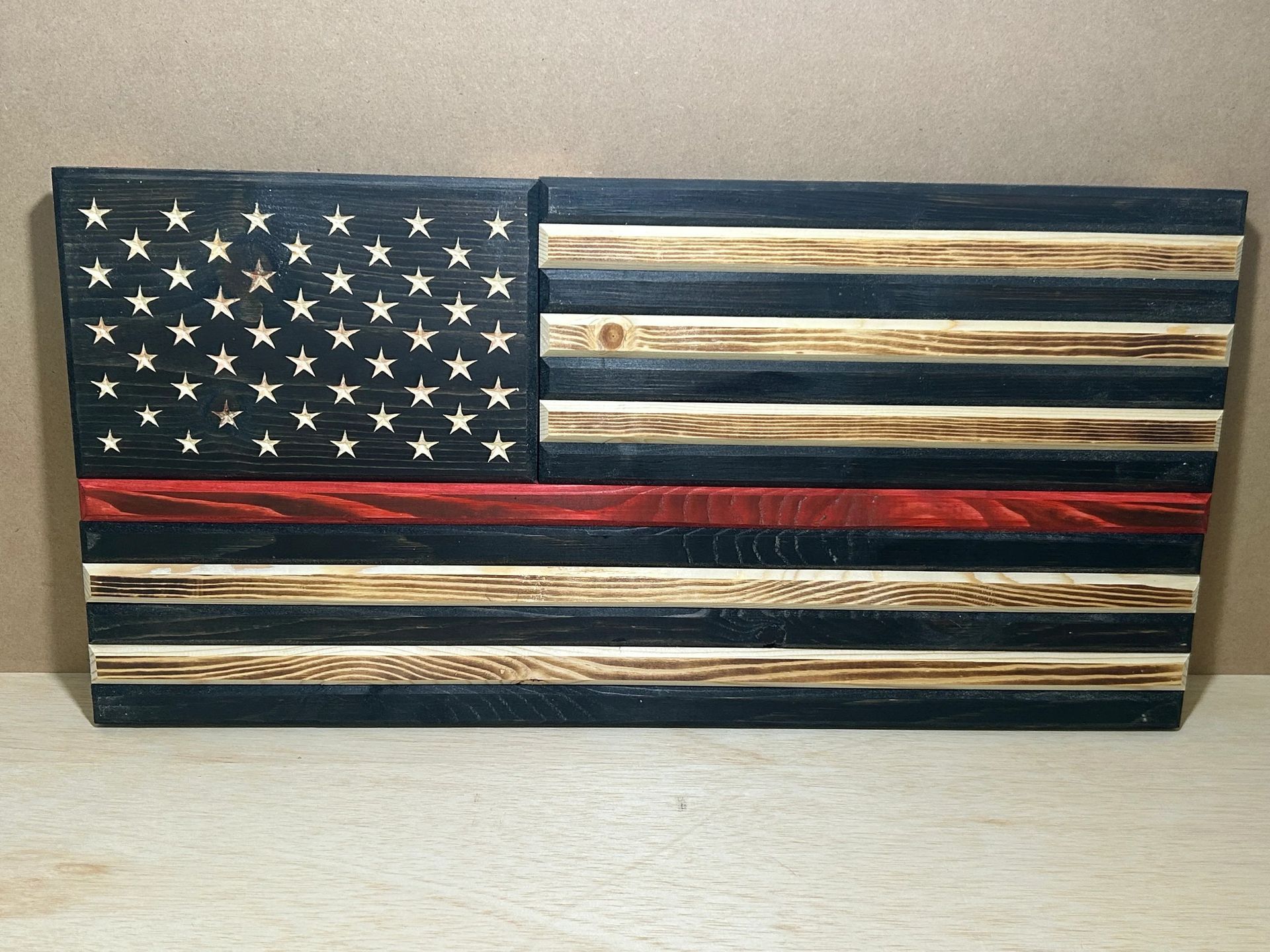 Wooden American flag with a red stripe, likely for firefighters. Black and wood-toned planks.
