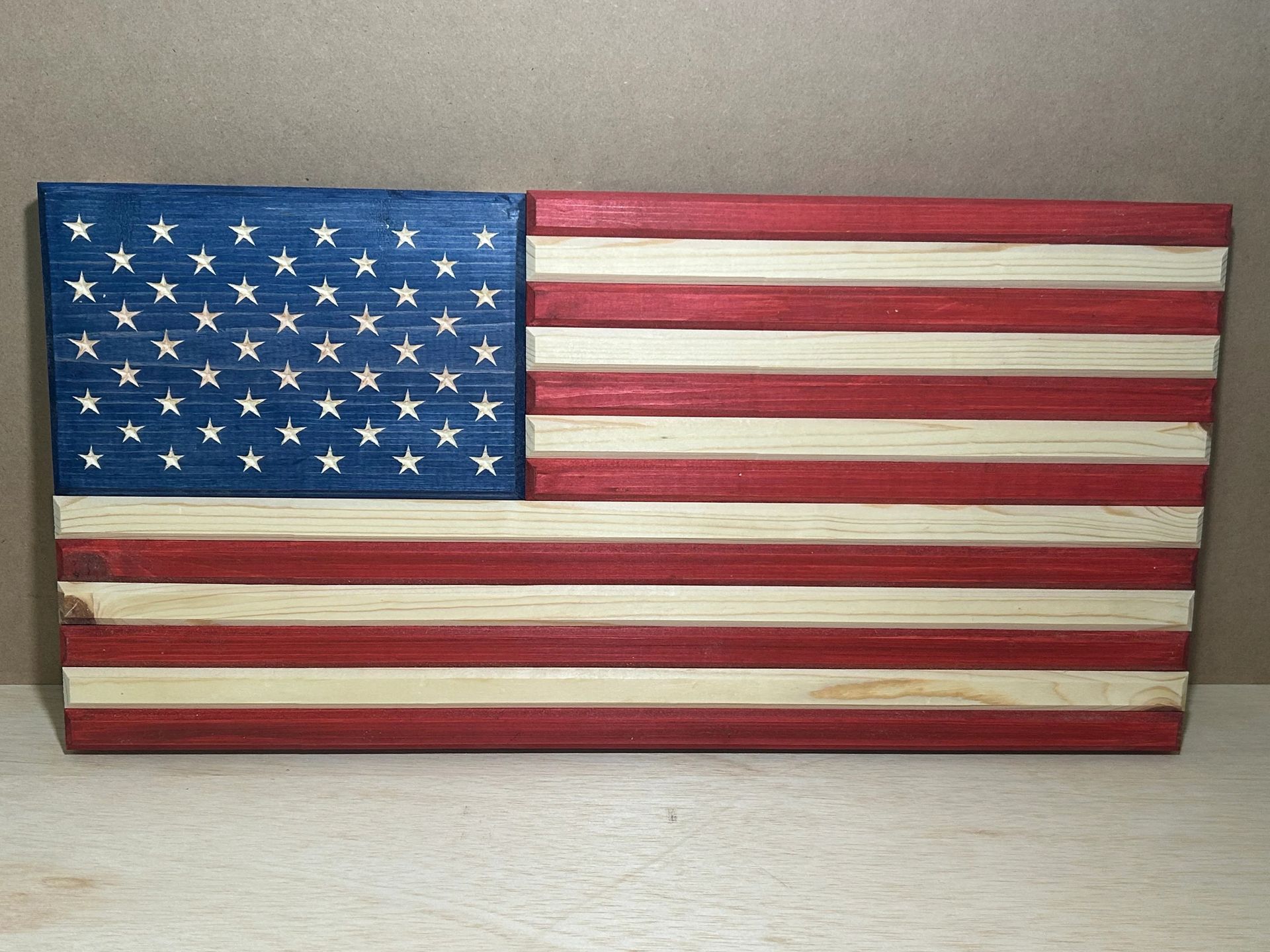 Wooden American flag, blue field with white stars, red and natural wood stripes.
