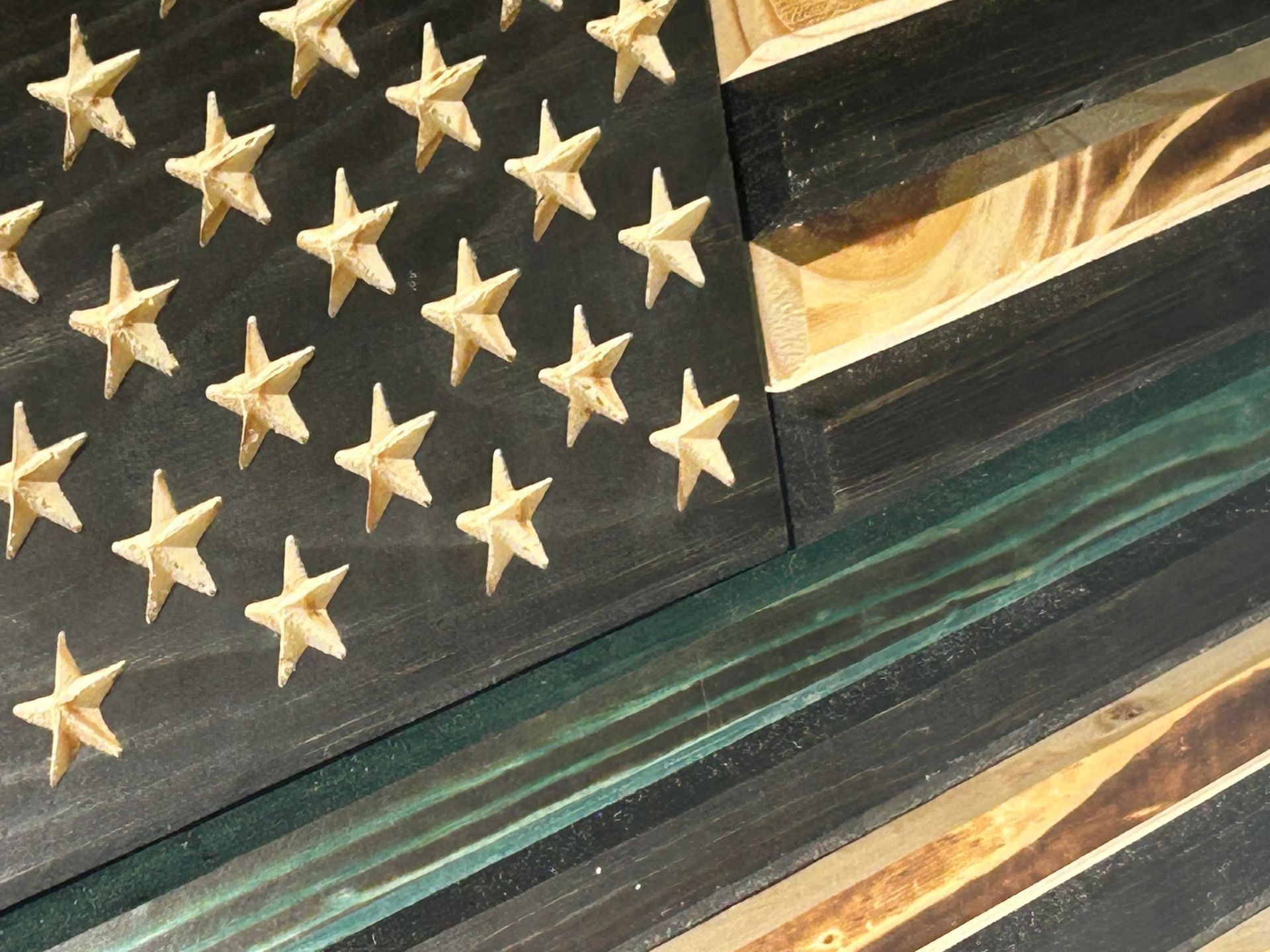 Wooden American flag with black, green, and natural wood stripes. Stars are carved out of the black field.