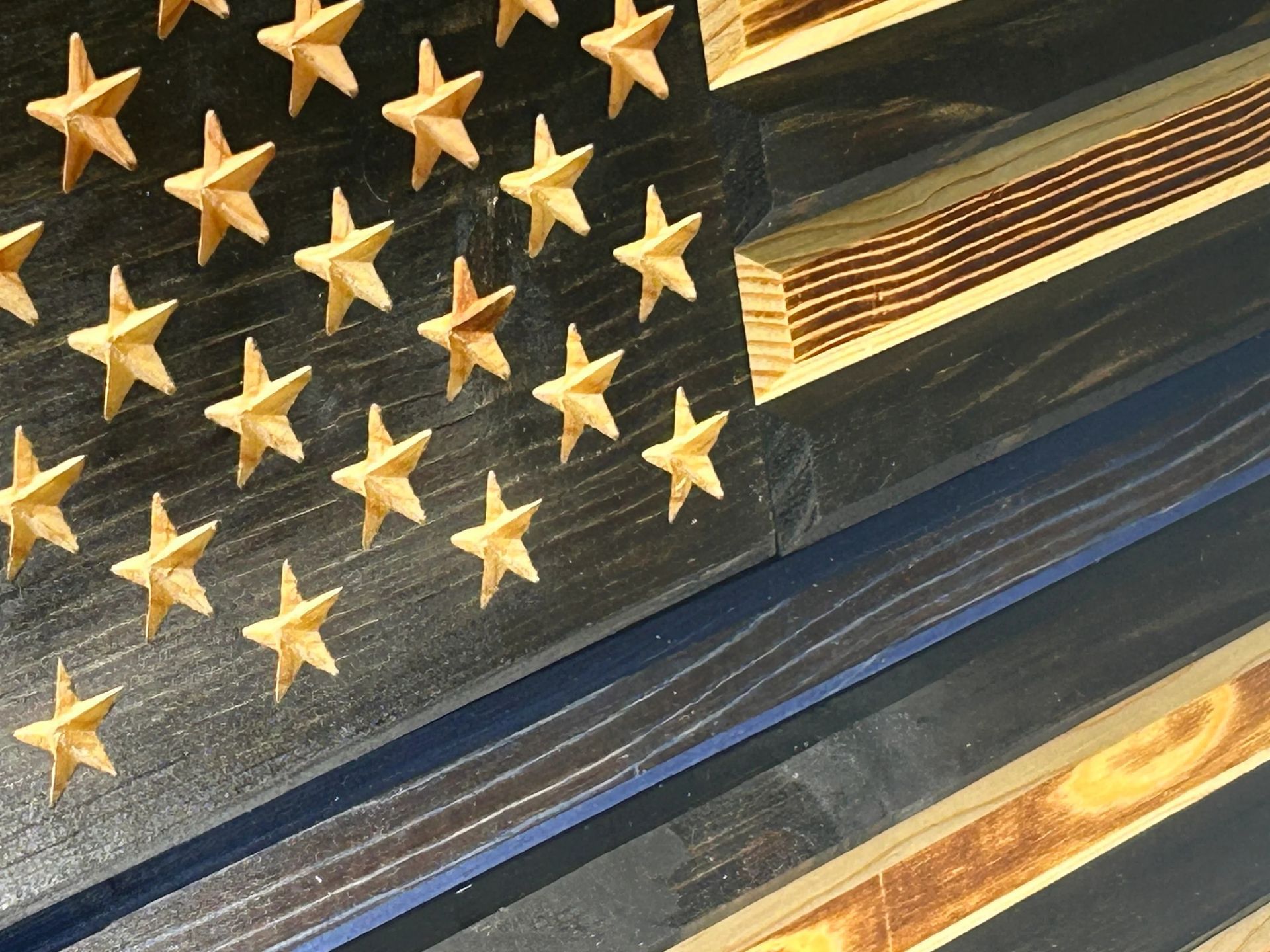 Wooden American flag with a blue line, with charred wood strips.