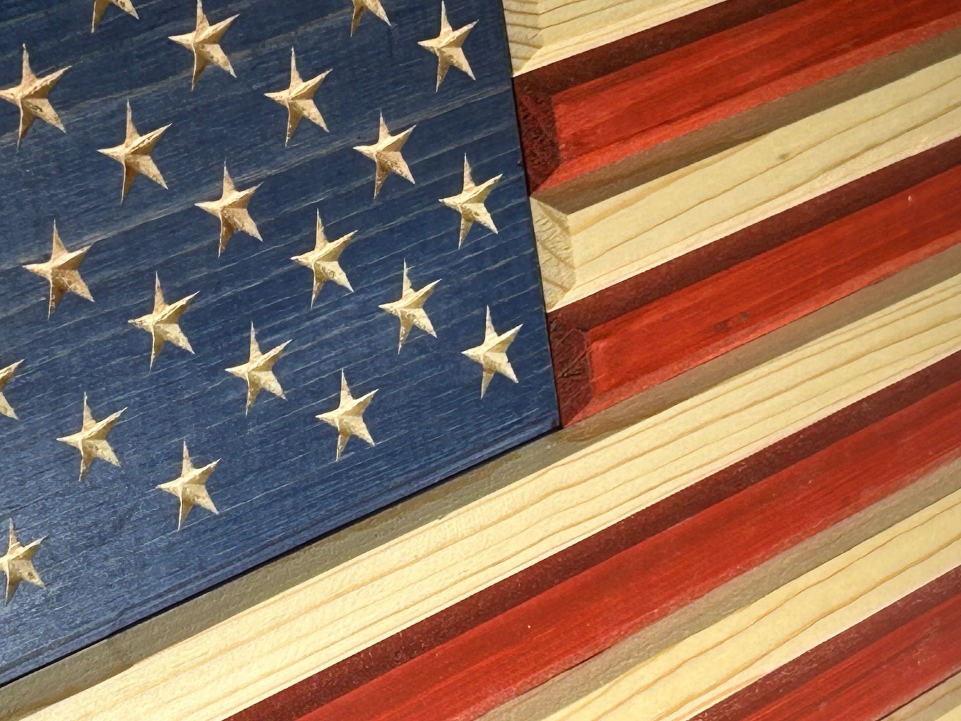 Wooden American flag, blue field with white stars, red and natural wood stripes.