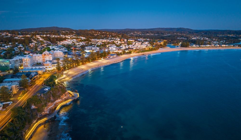 Coastal Town at Dusk With Lights Along the Beach and Cliffs — Enviro Clean Carpet and Tile Cleaning in Terrigal, NSW