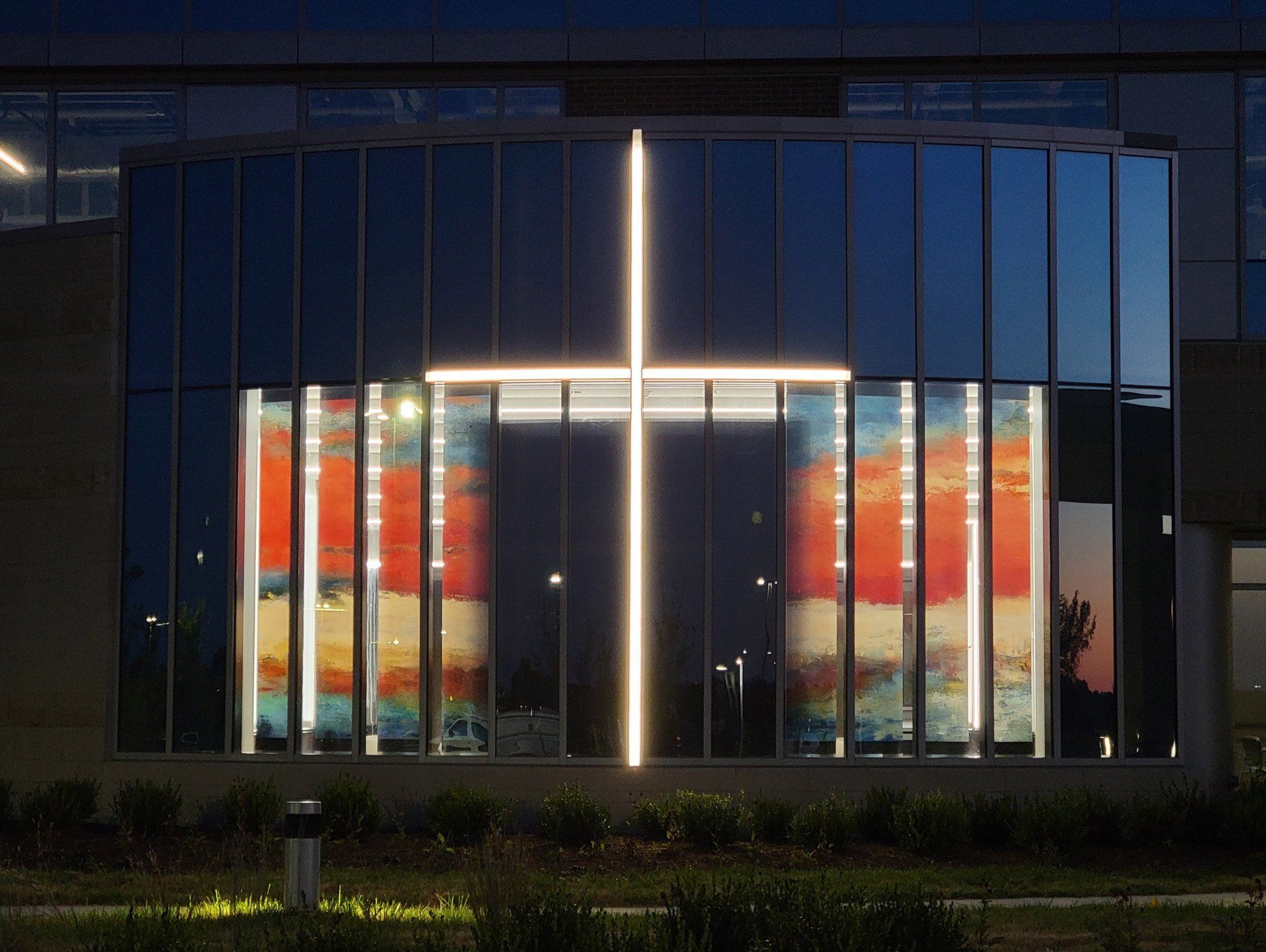 A cross is lit up in front of a building