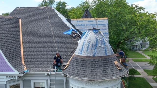 A group of men are working on the roof of a house.