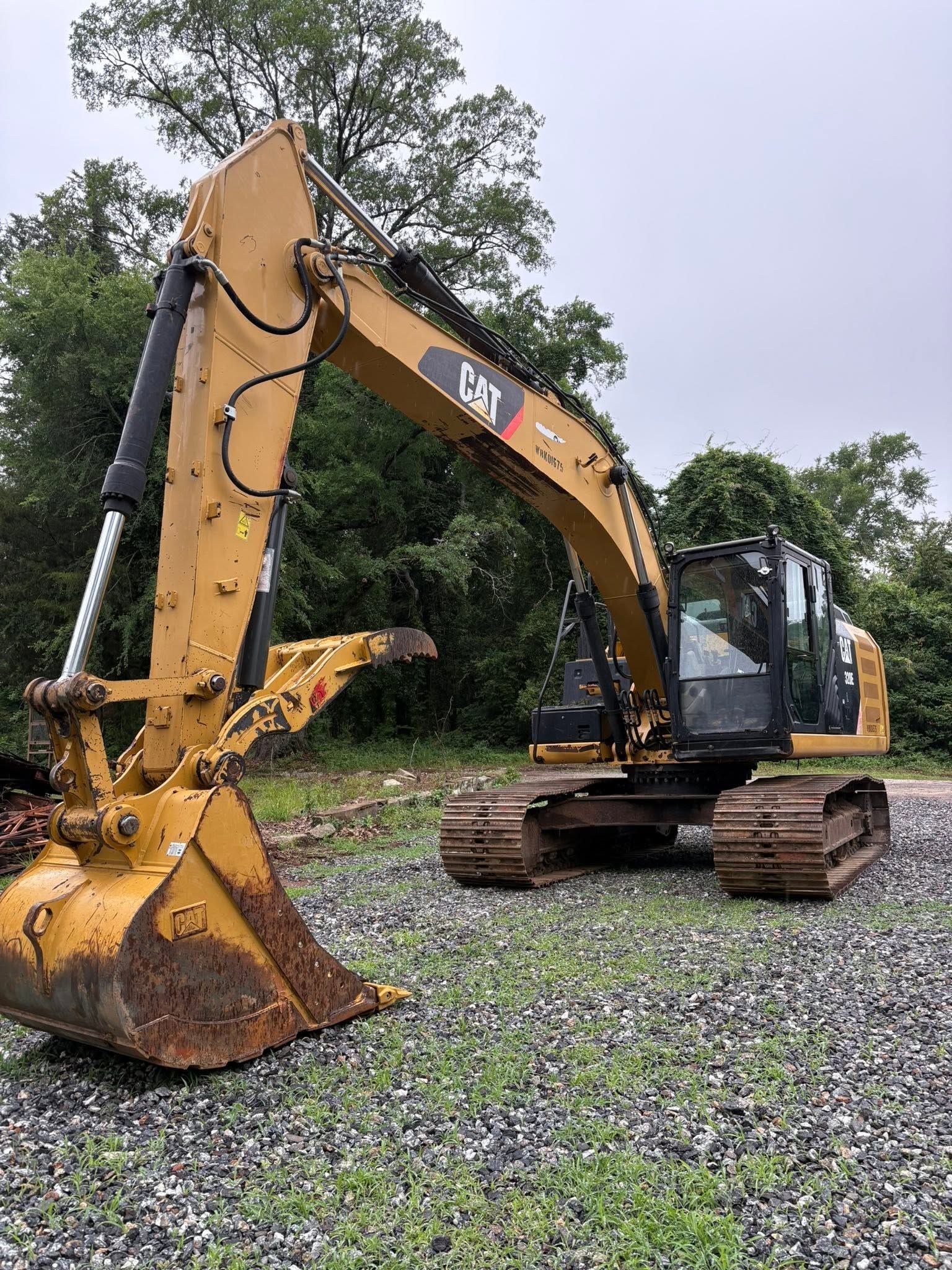 Yellow CAT excavator on a gravel lot with trees in the background.