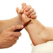 De voet van een persoon krijgt reflexologie met een houten instrument,