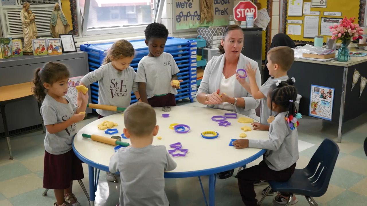 A group of children are sitting around a table with a stop sign in the background.