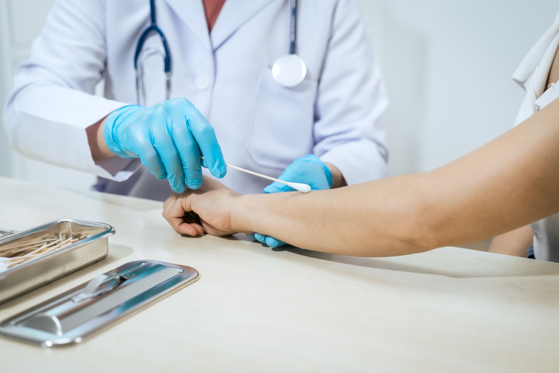 Healthcare provider cleans a minor arm wound with a cotton swab during a clinic visit. Healthcare provider cleans a minor arm wound with a cotton swab during a clinic visit.
