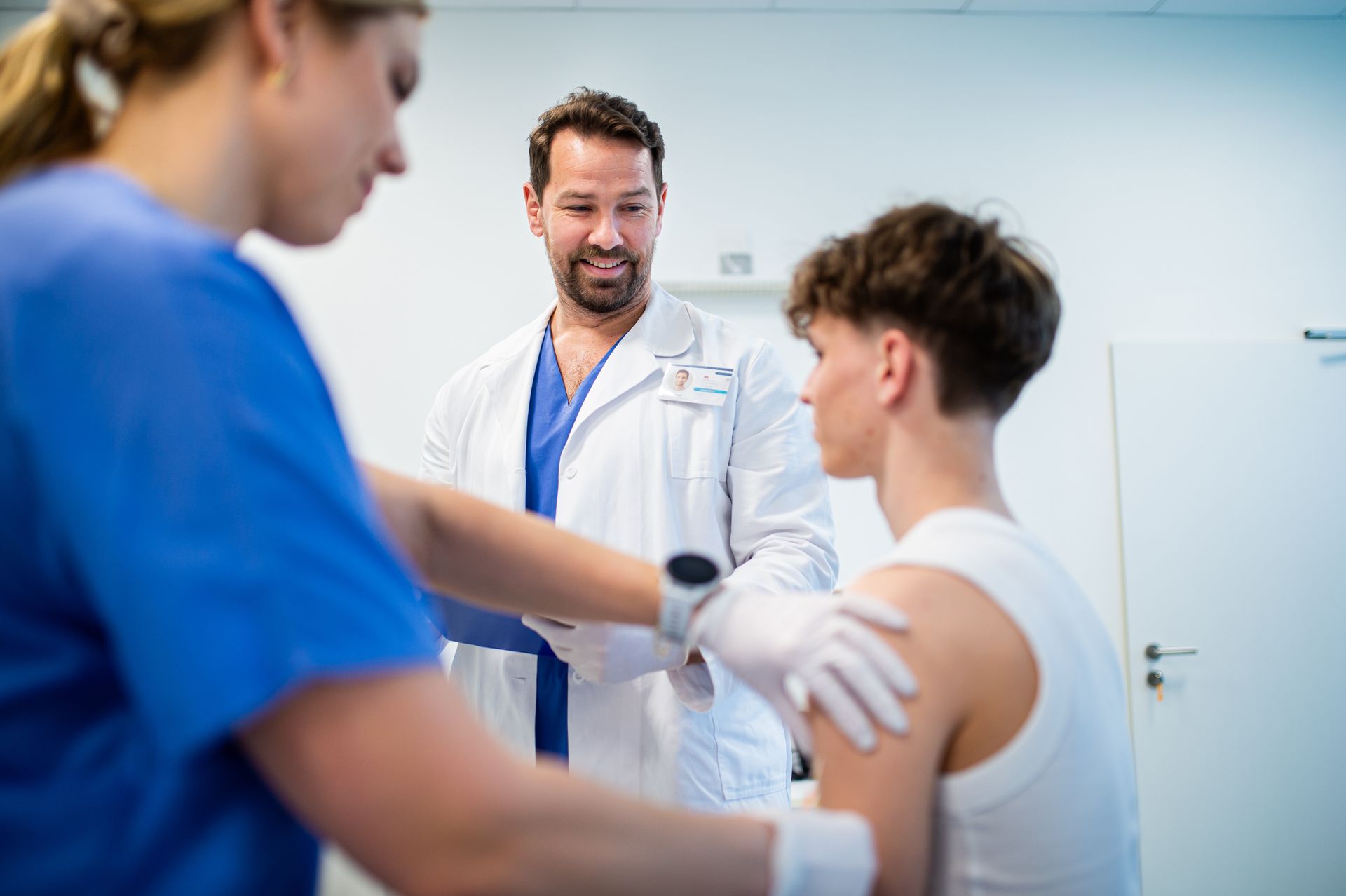 Doctor giving flu vaccine to teenage boy in medical clinic.