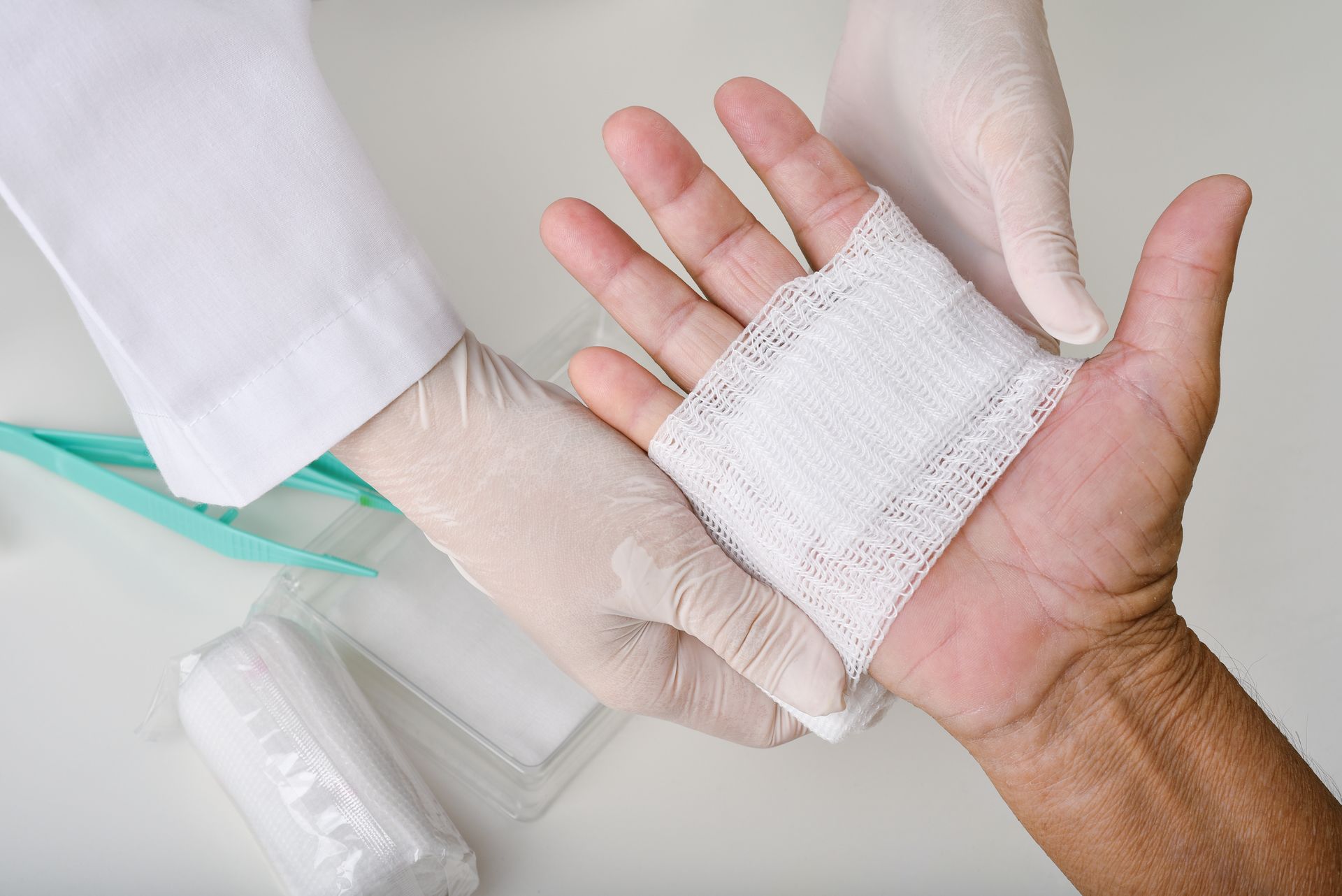 Medical professional wearing gloves applies a clean bandage to a patient’s injured hand.
