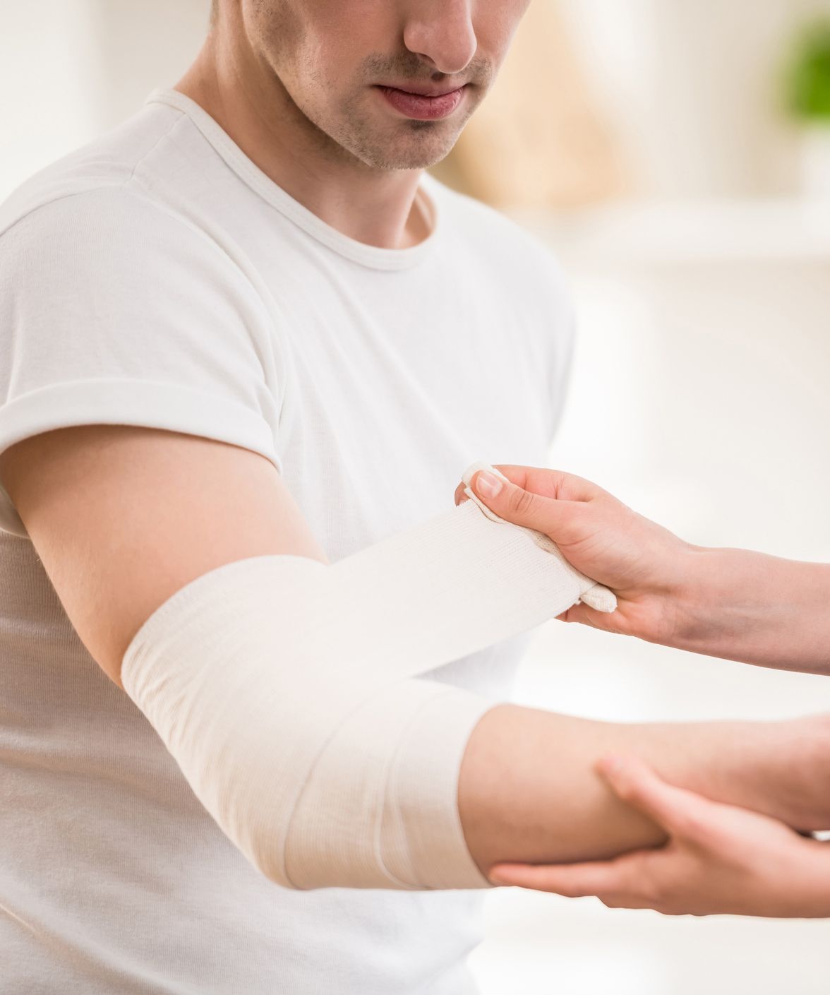 A man with a bandage on his elbow is being helped by a woman. A man with a bandage on his elbow is being helped by a woman.