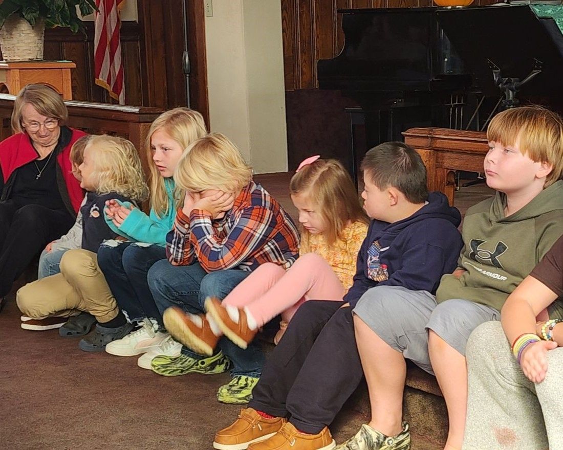 A group of children are sitting in a row on the floor
