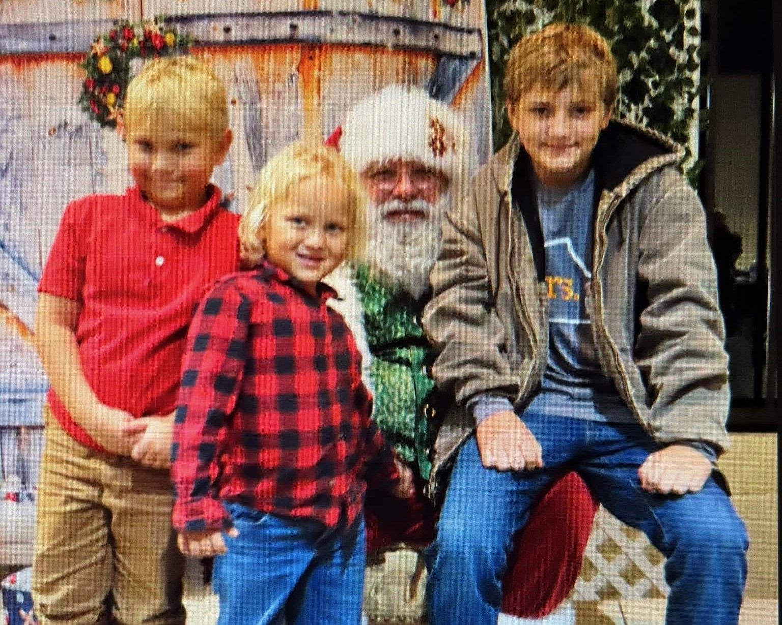 Three children are posing for a picture with santa claus