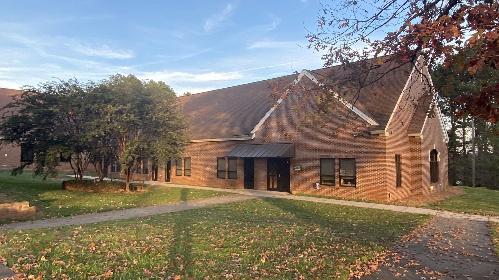 A large brick building with a lot of windows and trees in front of it.