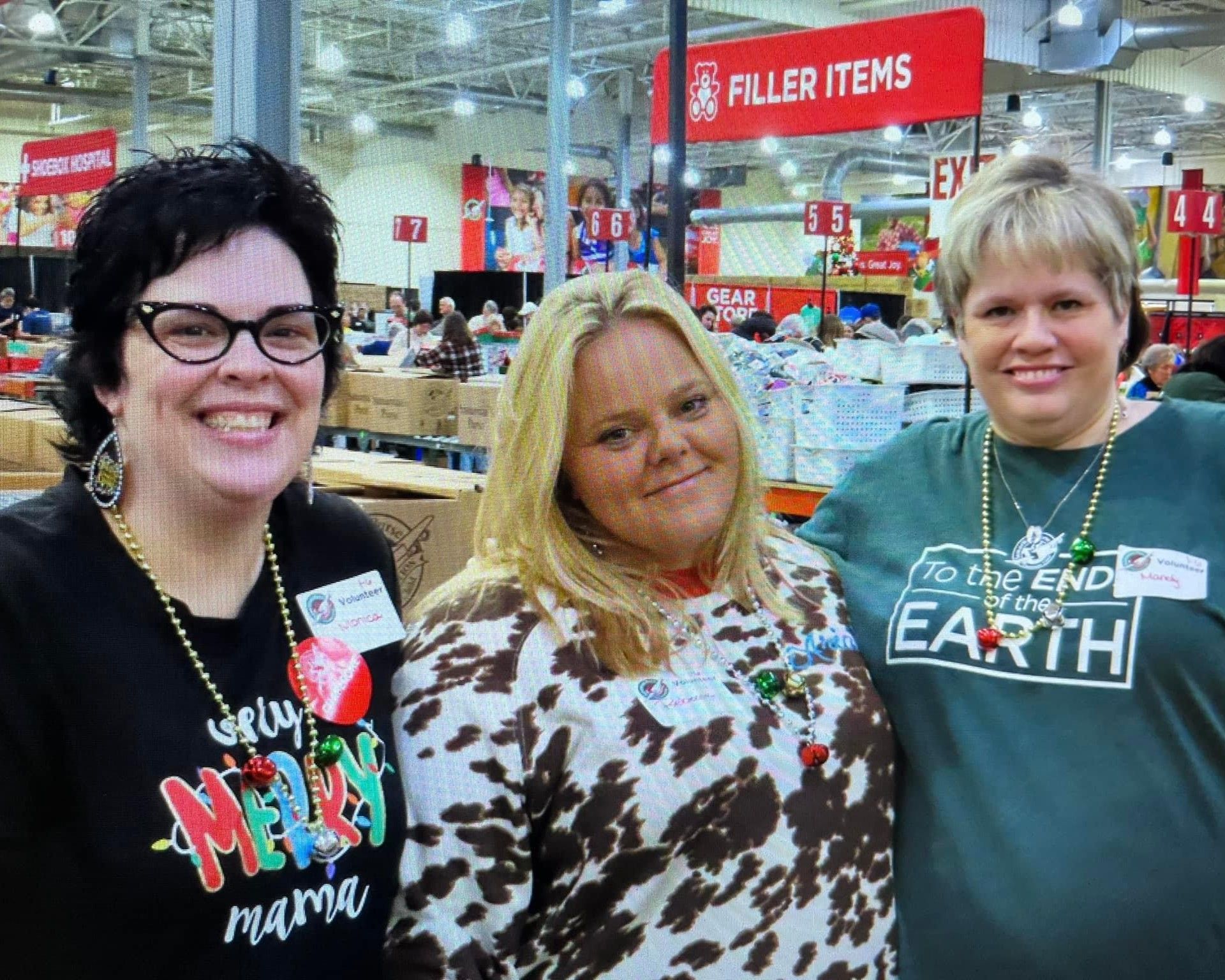 Three women are posing for a picture in front of a filler items sign.