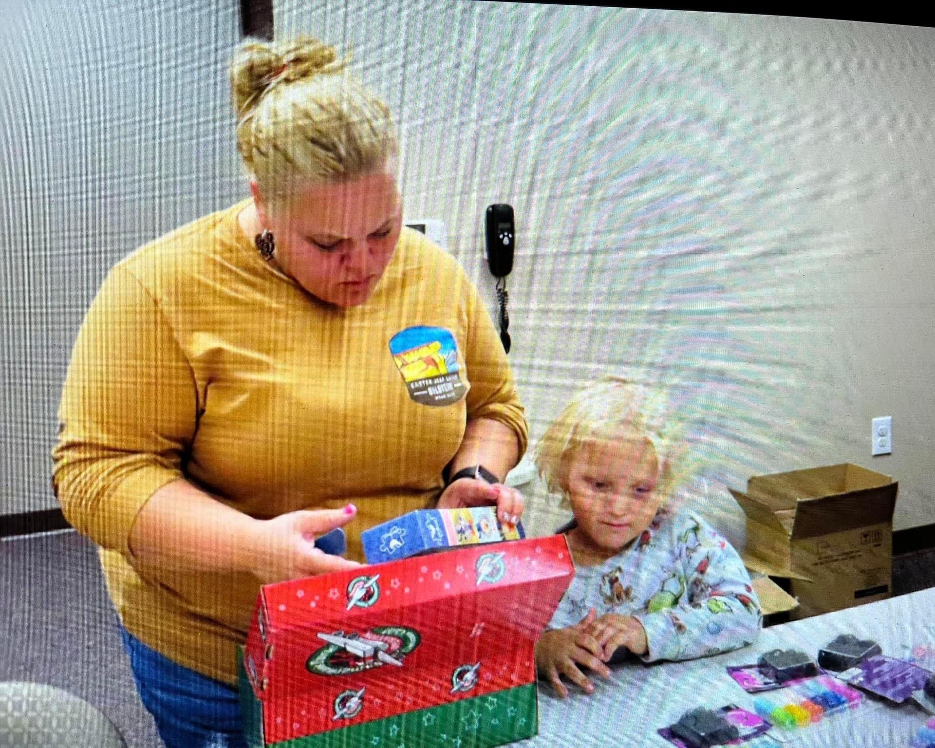 A woman and a little girl are opening a christmas box.