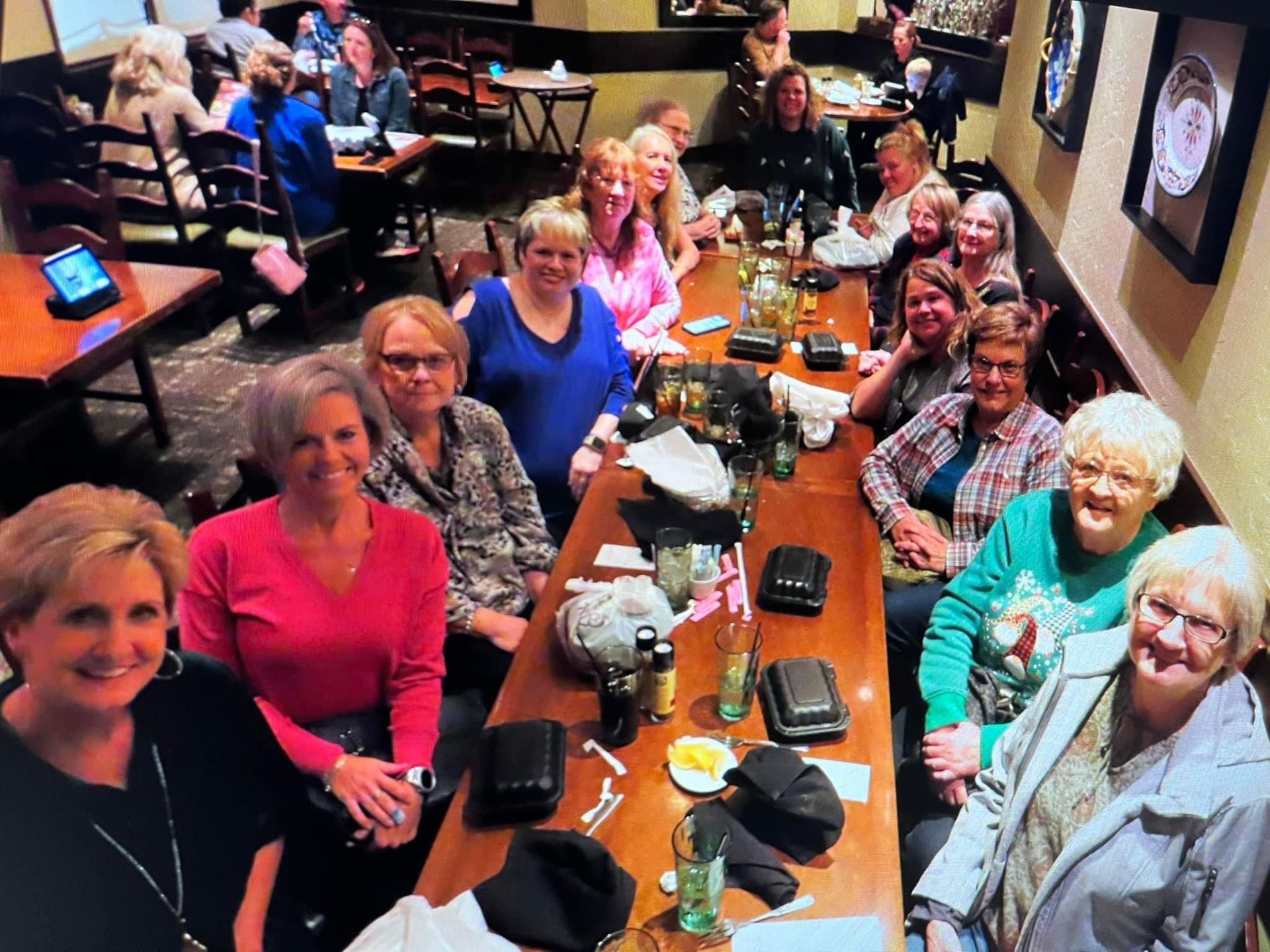 A group of women are sitting at a long table in a restaurant