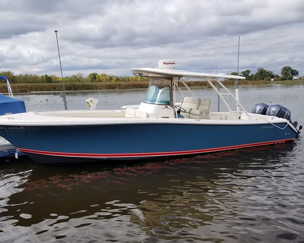 Blue and white motorboat floating on calm water under a cloudy sky