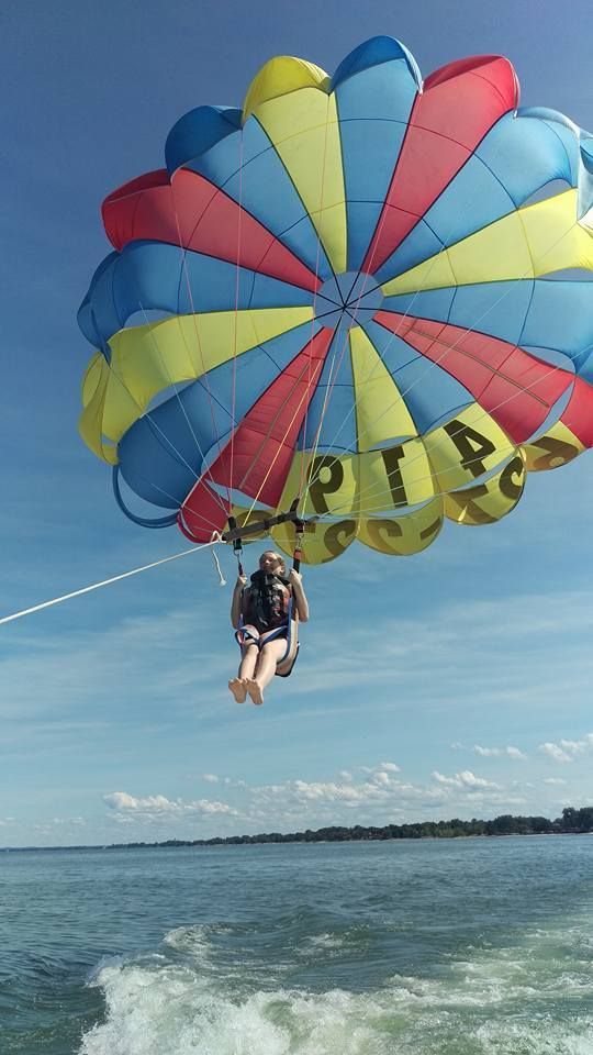 Person parasailing under a colorful blue, yellow, and red canopy over the ocean