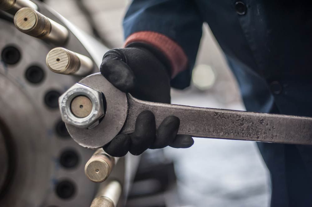 Mechanic At The Factory Screws Big Bolt With Heavy Wrench