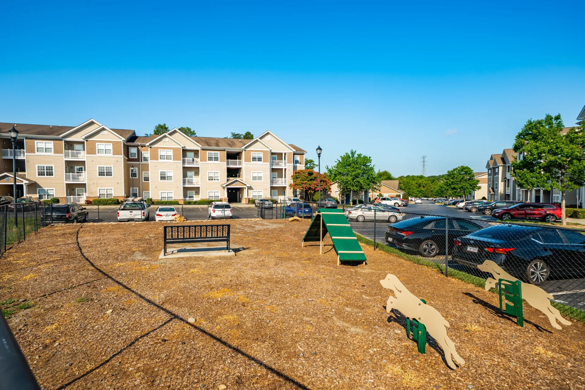 Dog park with agility equipment and apartment buildings in the background.
