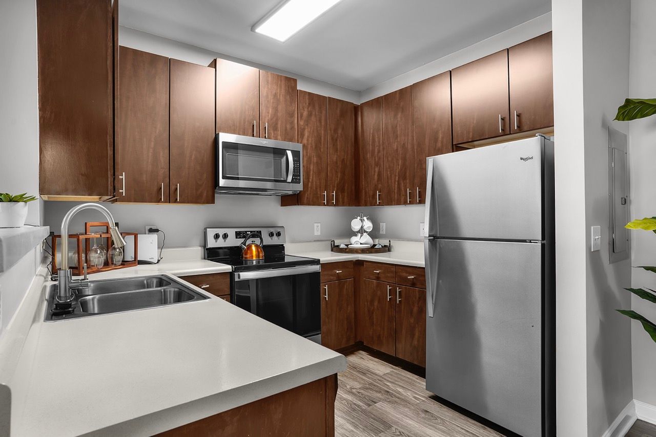 Modern apartment kitchen with dark wood cabinets and stainless steel appliances at Reserve at Stone Hollow in Charlotte, NC.