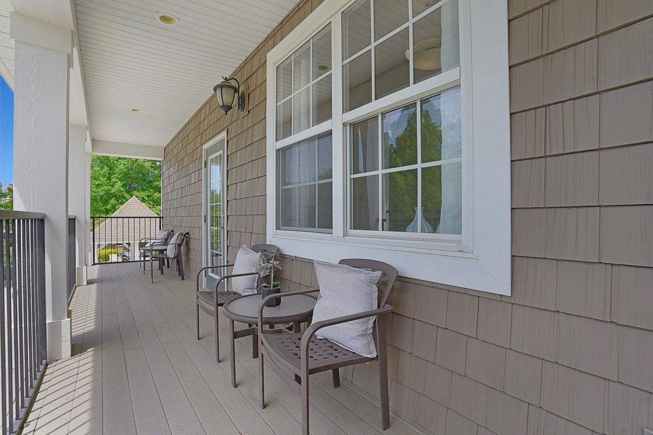Outdoor apartment balcony with metal chairs and cushions along a shingled wall at Reserve at Stone Hollow in Charlotte, NC.