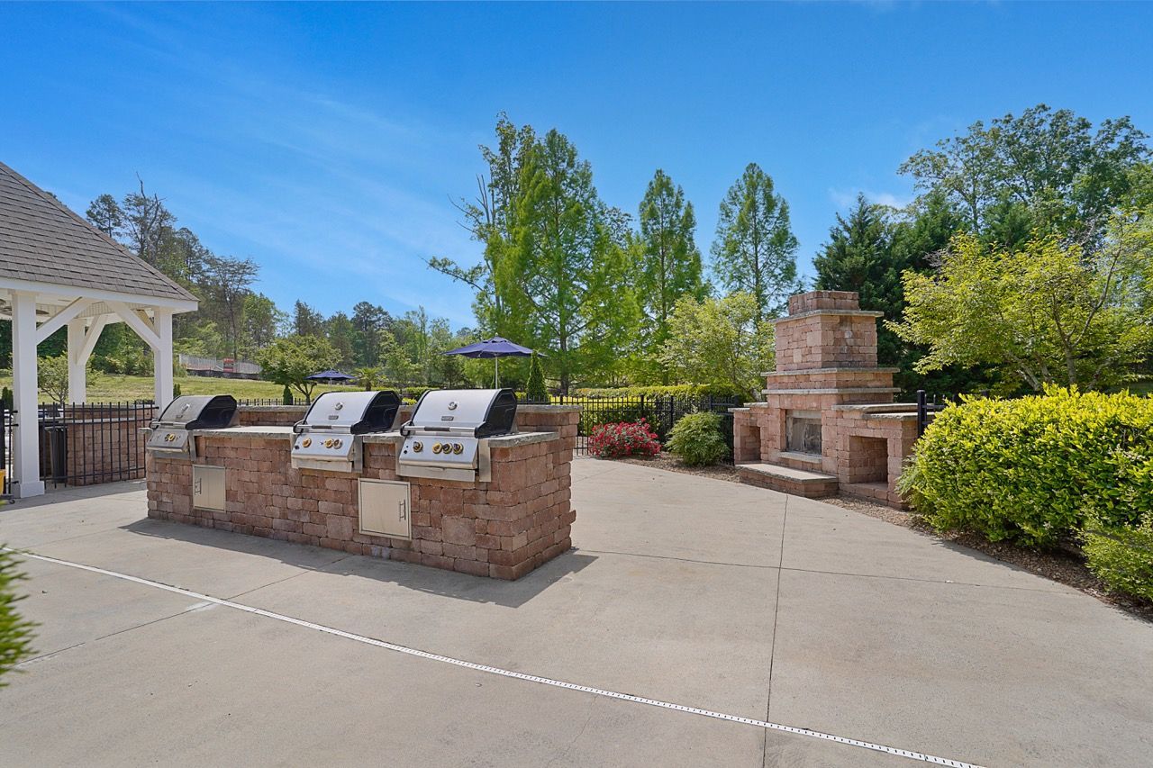 Outdoor communal grilling area with three brick grills and a stone fireplace at Reserve at Stone Hollow in Charlotte, NC.