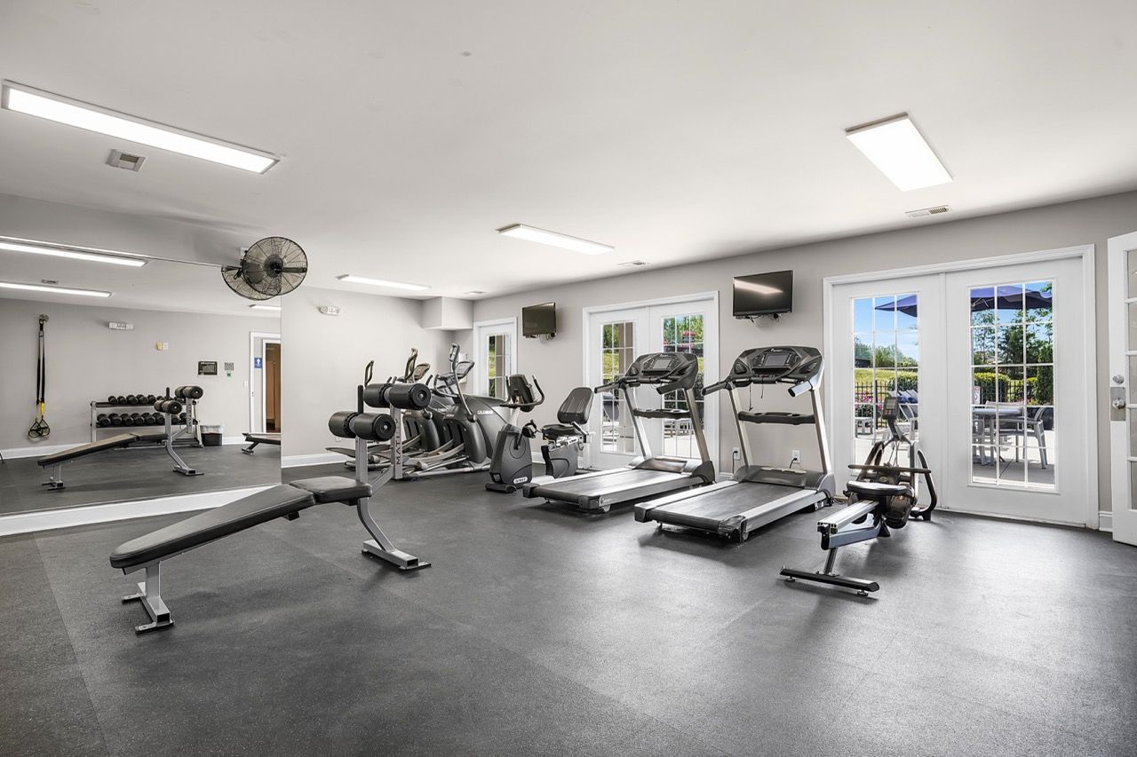 Interior community gym with cardio machines, free weights, and benches at Reserve at Stone Hollow in Charlotte, NC.