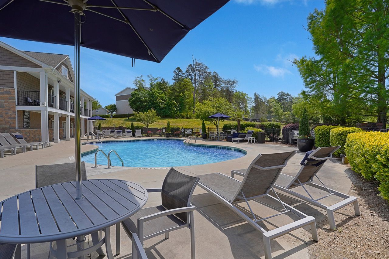 Outdoor pool at a multifamily community with lounge chairs and umbrellas at Reserve at Stone Hollow in Charlotte, NC.