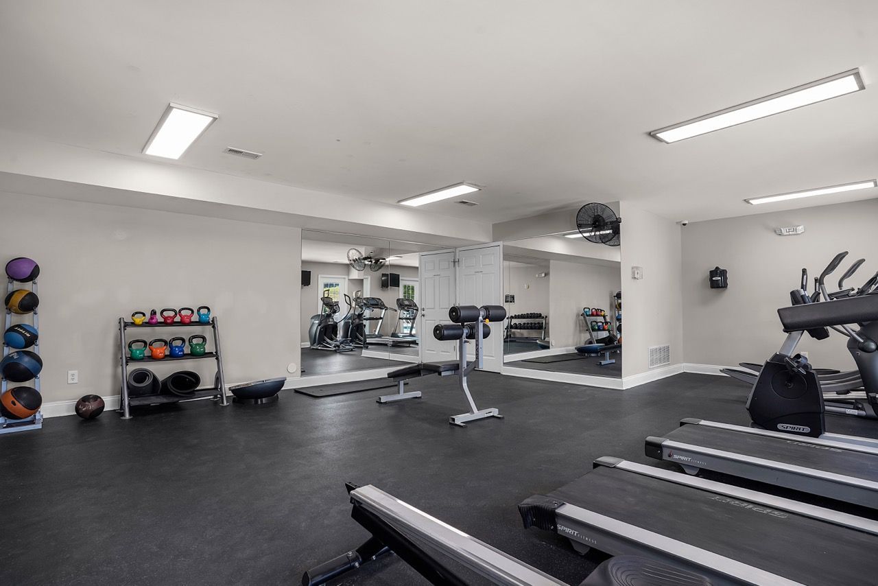 Interior of a resident gym with treadmills, weights, and mirrors at Reserve at Stone Hollow in Charlotte, NC.