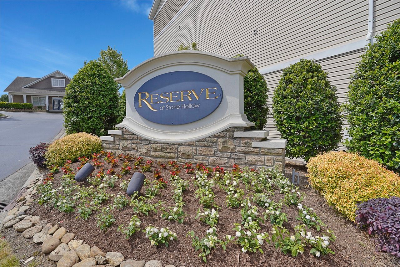 Exterior sign for Reserve at Stone Hollow with landscaped flower bed at Reserve at Stone Hollow in Charlotte, NC.