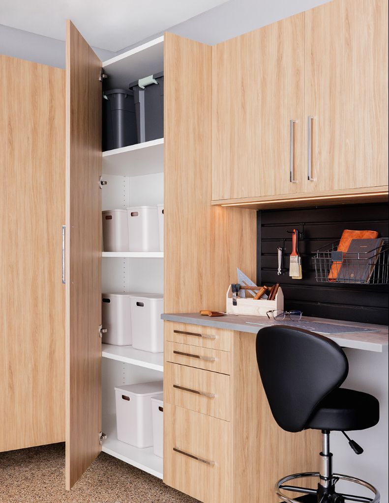 Built-in wood desk and cabinets with shelves, drawers, and a black office chair in a home workspace.