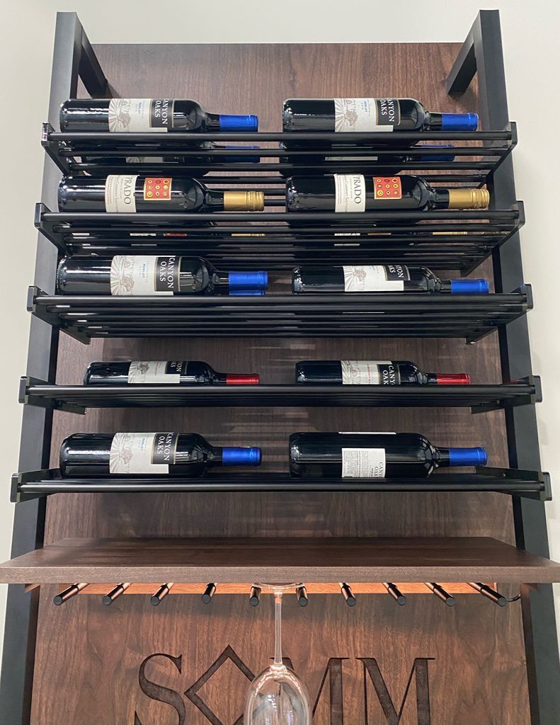 Wall-mounted wine rack with several bottles stored horizontally above a wooden cabinet