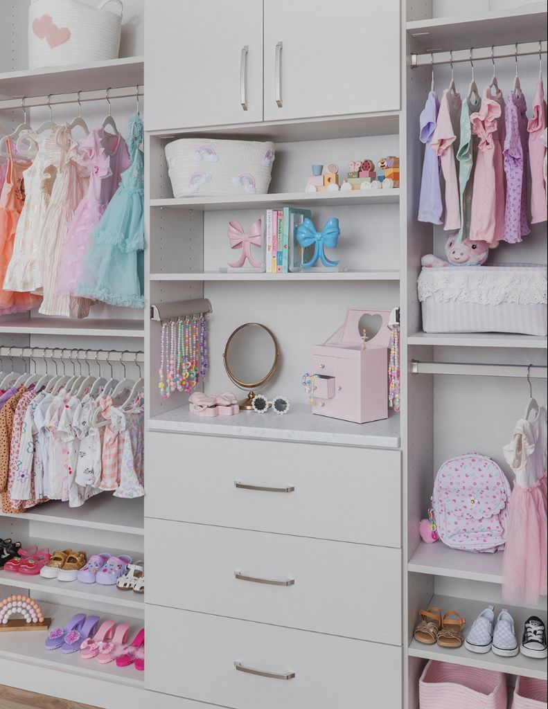 Organized pink-and-white children’s closet with hanging clothes, shelves, drawers, shoes, and accessories