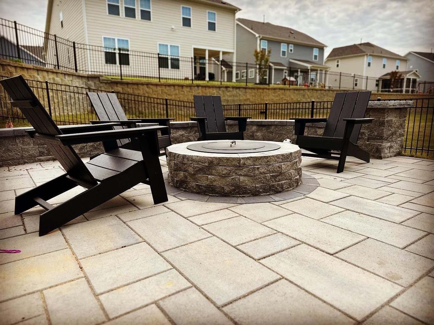 There is a fire pit on the patio with chairs around it.