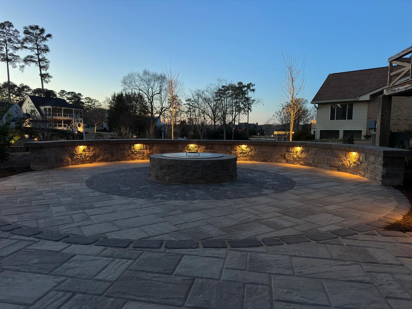 A brick patio with a fire pit in the middle of it