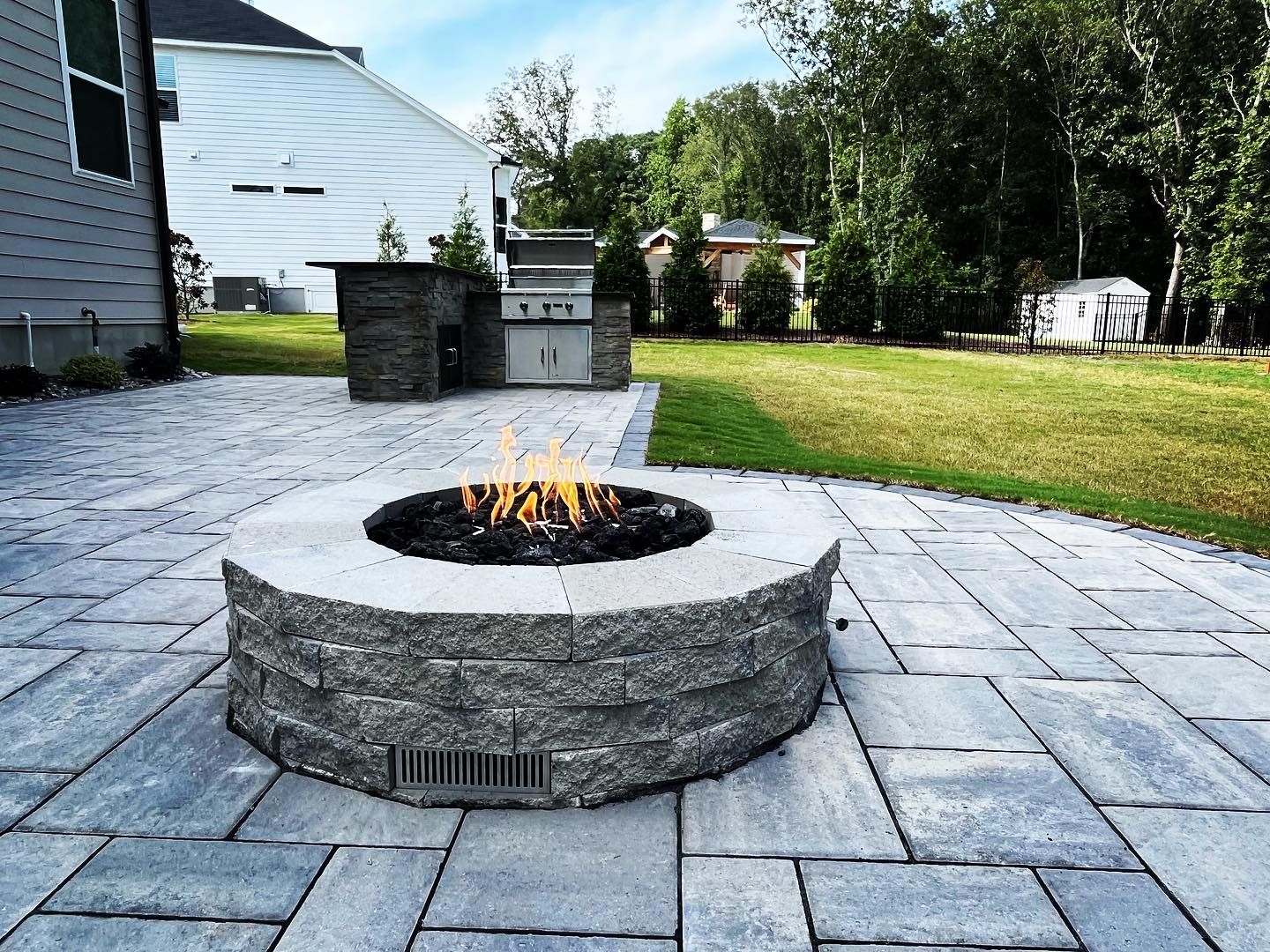 A fire pit is sitting on a patio next to a house.