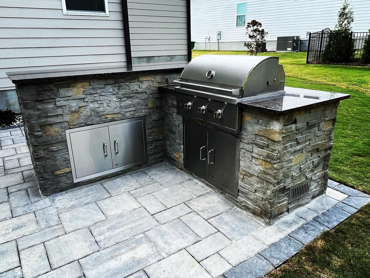 A grill is built into a stone wall on a patio.
