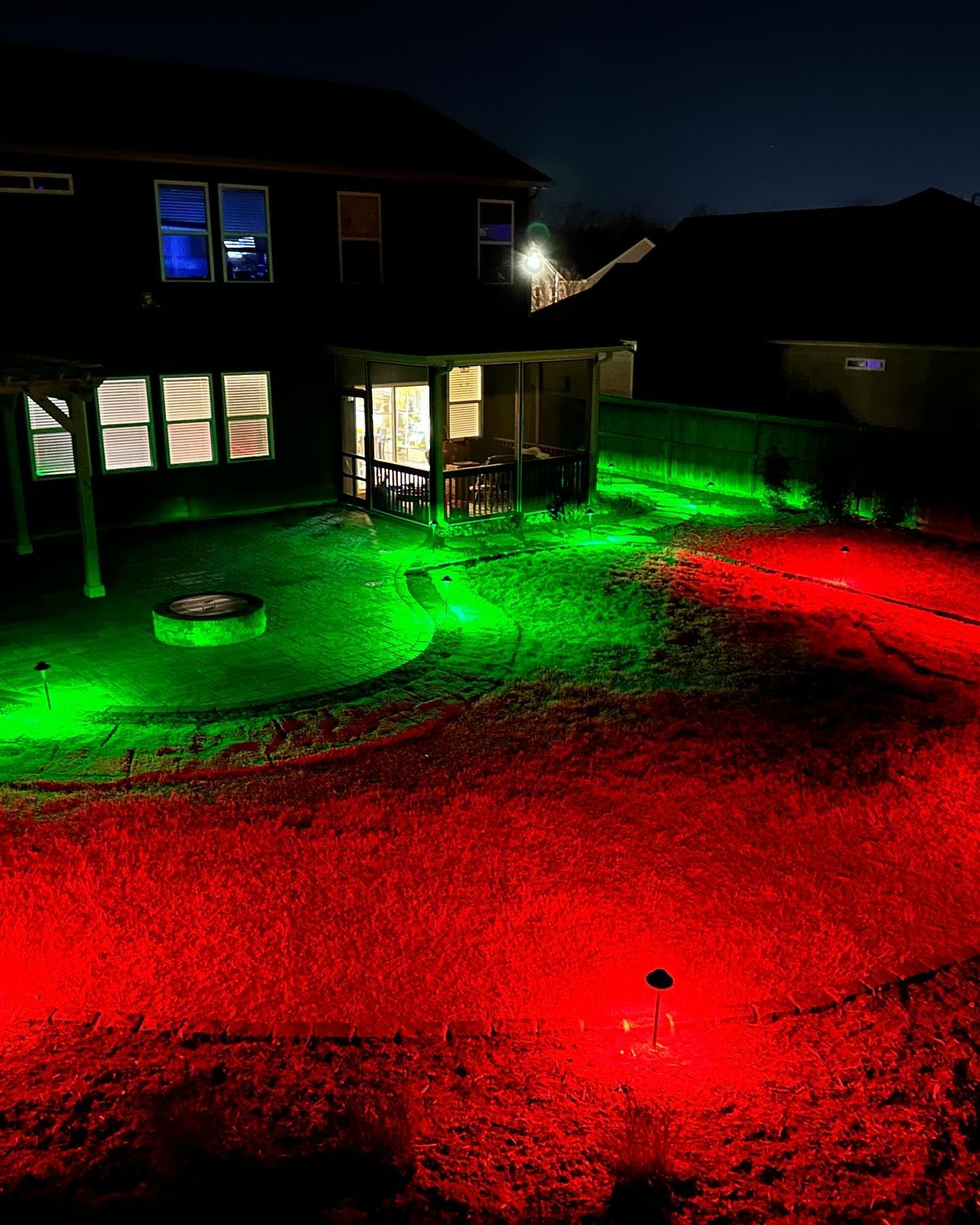 The backyard of a house is lit up with red and green lights at night.
