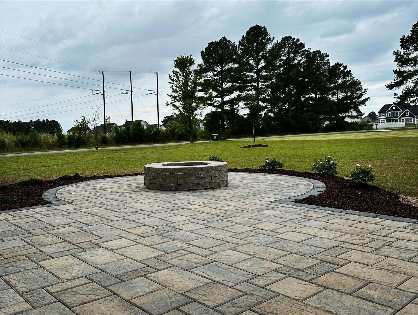 A brick patio with a fire pit in the middle of it