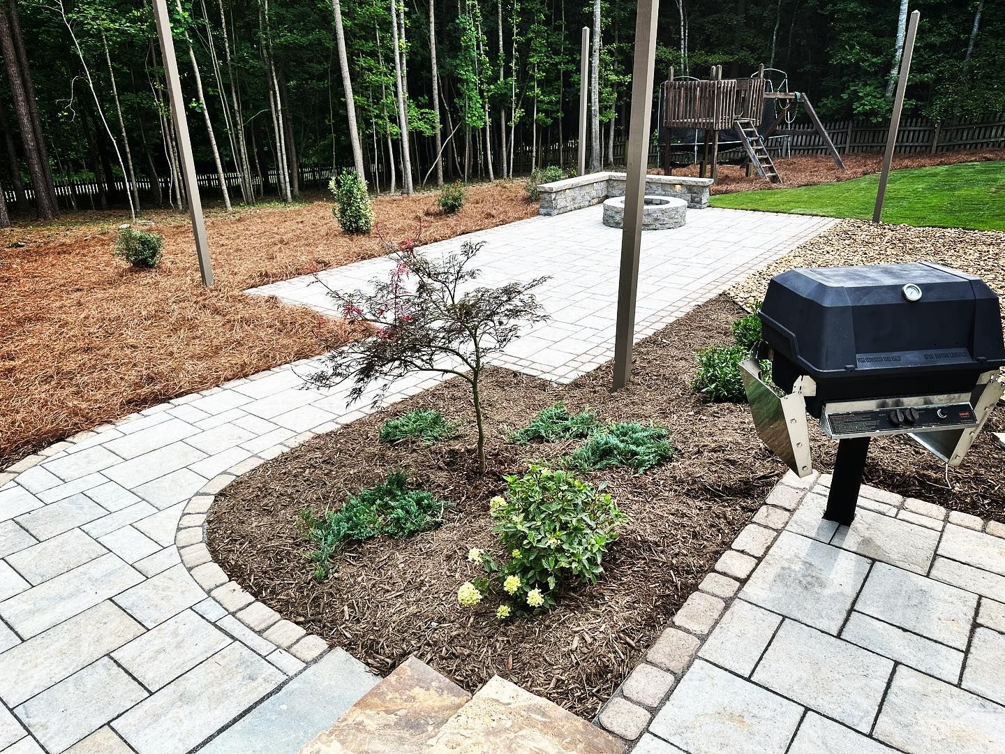 A patio with a grill and a fire pit in the backyard.