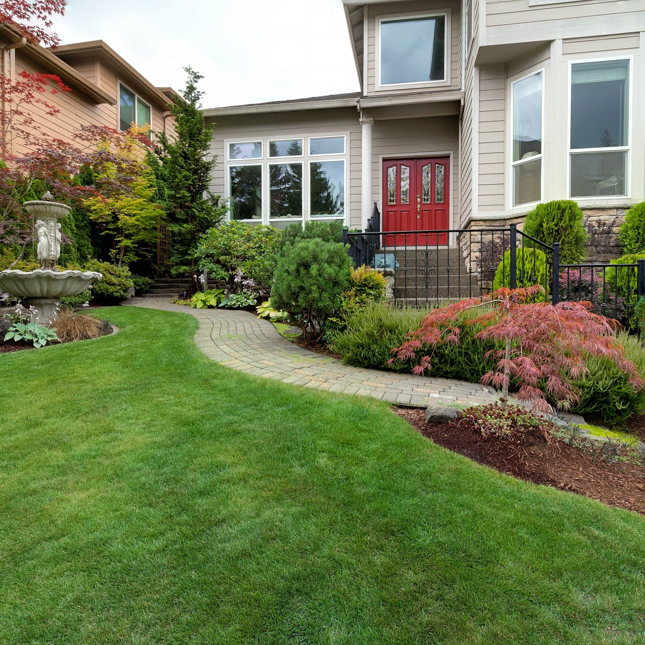 A house with a lush green lawn and a red door