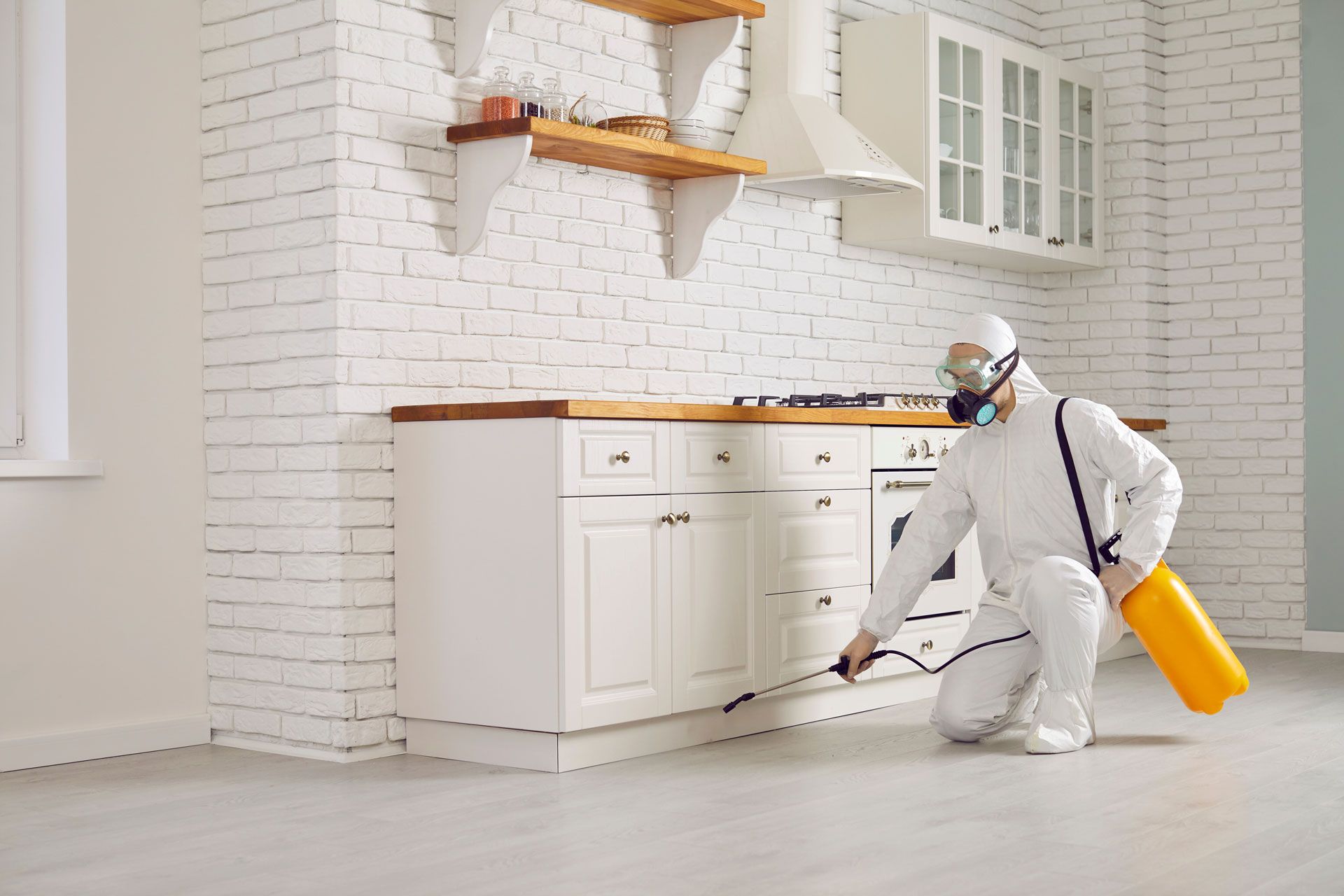 Person in hazmat suit spraying kitchen with pesticide.