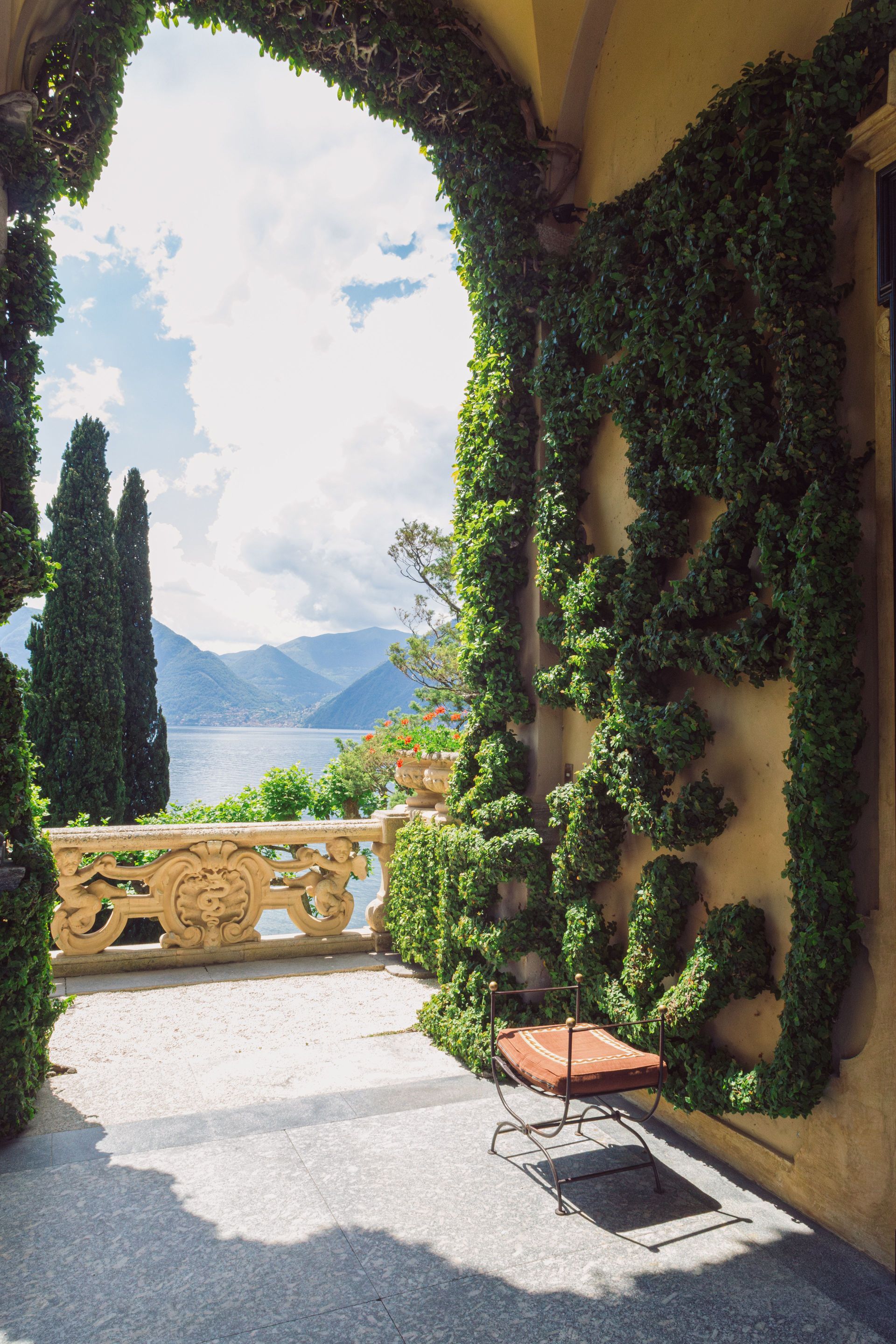 Ivy-covered archway opening to a sunny terrace with mountain and water views